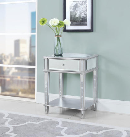 Emit a glamorous glow from this silver accent table, complete with reflective mirrored pieces. The stylishly tapered legs are connected with a built-in storage shelf. Complete with one drawer, this table features delicate crystal-like hardware. Open up a room with the charming fronts and sides from the top and legs. Complete a chic motif or add a pop of glam to a modern space.